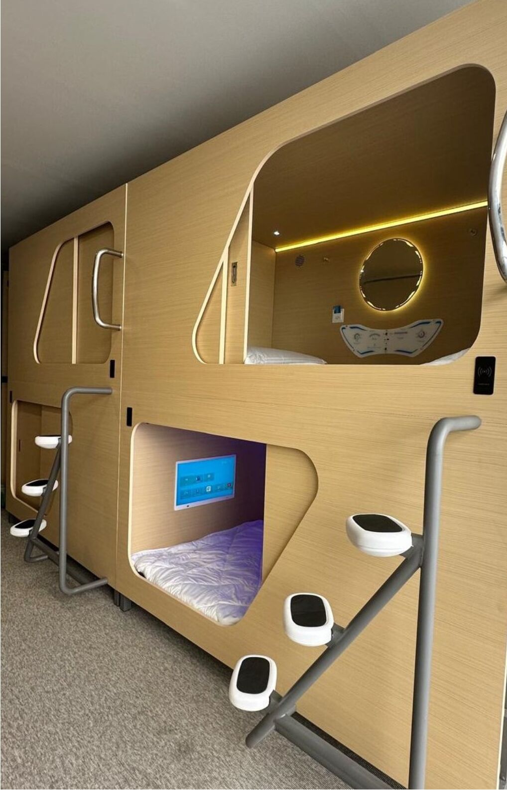 A modern, multi-level bunk bed room with built-in storage compartments and a digital control panel.