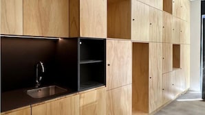 A modern kitchen with wooden cabinetry and a black countertop. - Urban Cube Hostel Sevilla (Seville)