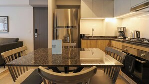 A modern kitchen with granite countertops, stainless steel appliances, and a dining area with a table and chairs. - w* | Fabulous 2BR w/ Impressive Deco in San Isidro (San Isidro)