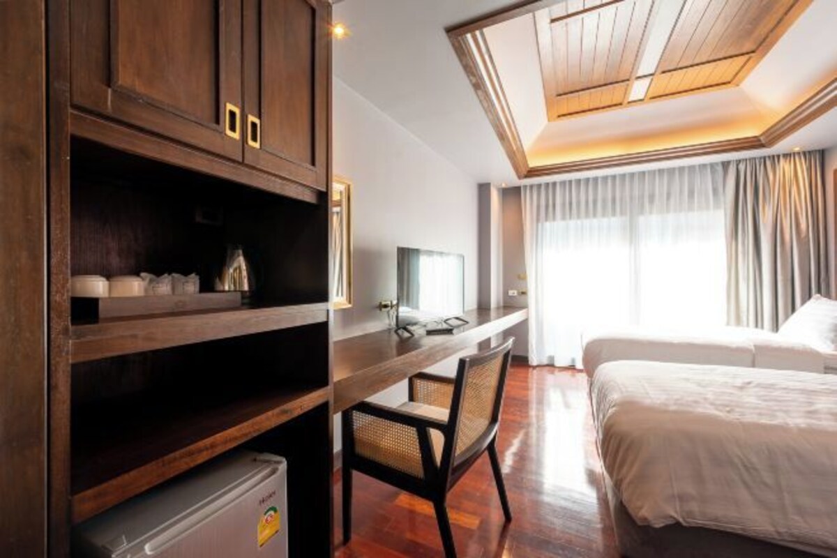 A hotel room with a wooden desk, a chair, a bed, and a television.