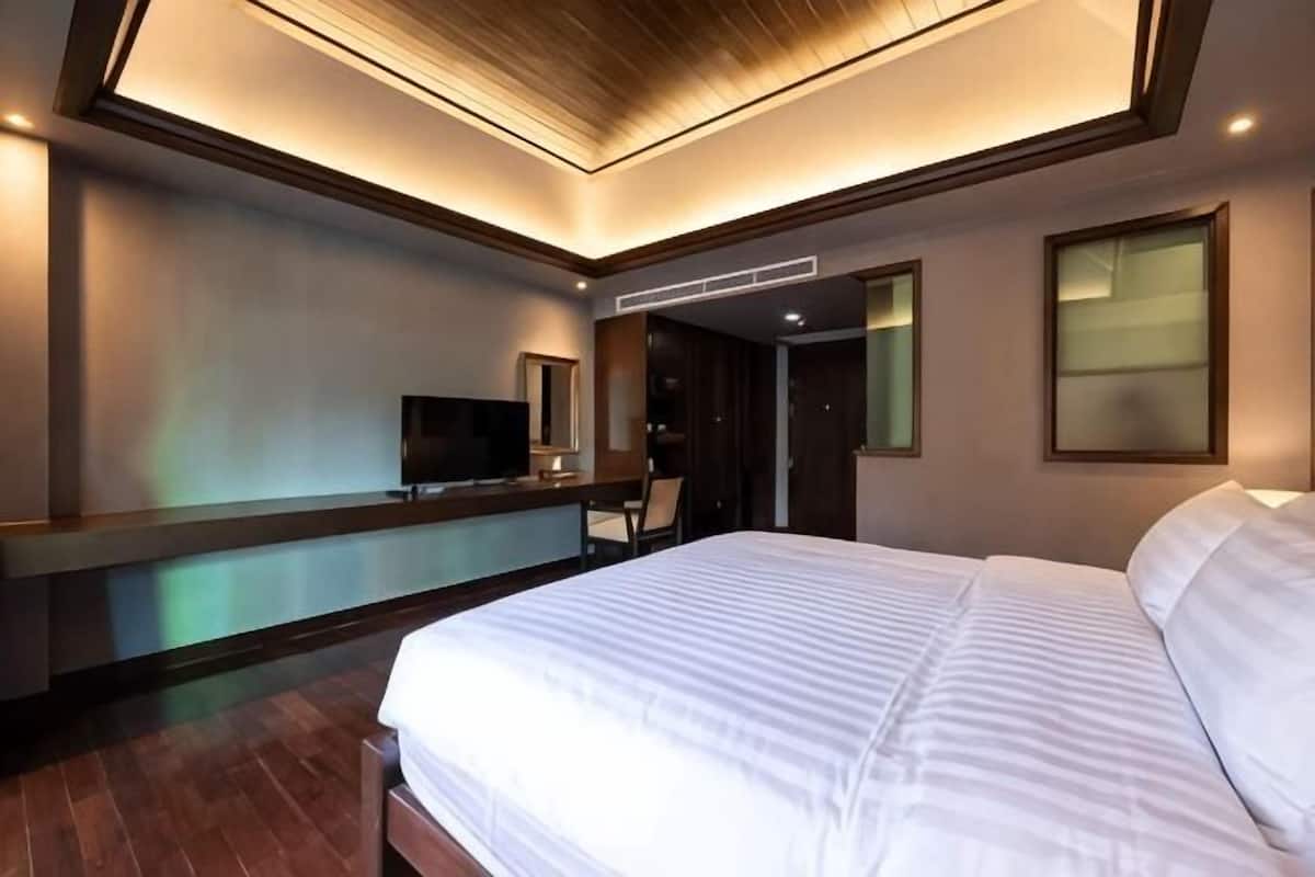 Habitació d'hotel moderna amb un llit gran, escriptori, televisió de pantalla plana i un armari encastat.