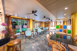 A modern dining area with ceiling fans, a variety of seating options, and a view of the outdoors. - At Gate Thaphae Hotel (Chiang Mai)