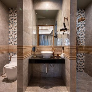 A bathroom with a freestanding bathtub, a sink with a mirror, and a toilet. - At Gate Thaphae Hotel (Chiang Mai)
