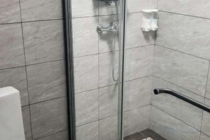 A shower area with a glass door, a handheld showerhead, and a grab bar. - Yongzhou Xiangjiang Hotel (Yongzhou)