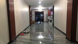 Un pasillo con suelo de mármol brillante, puertas de madera y una lámpara iluminada.