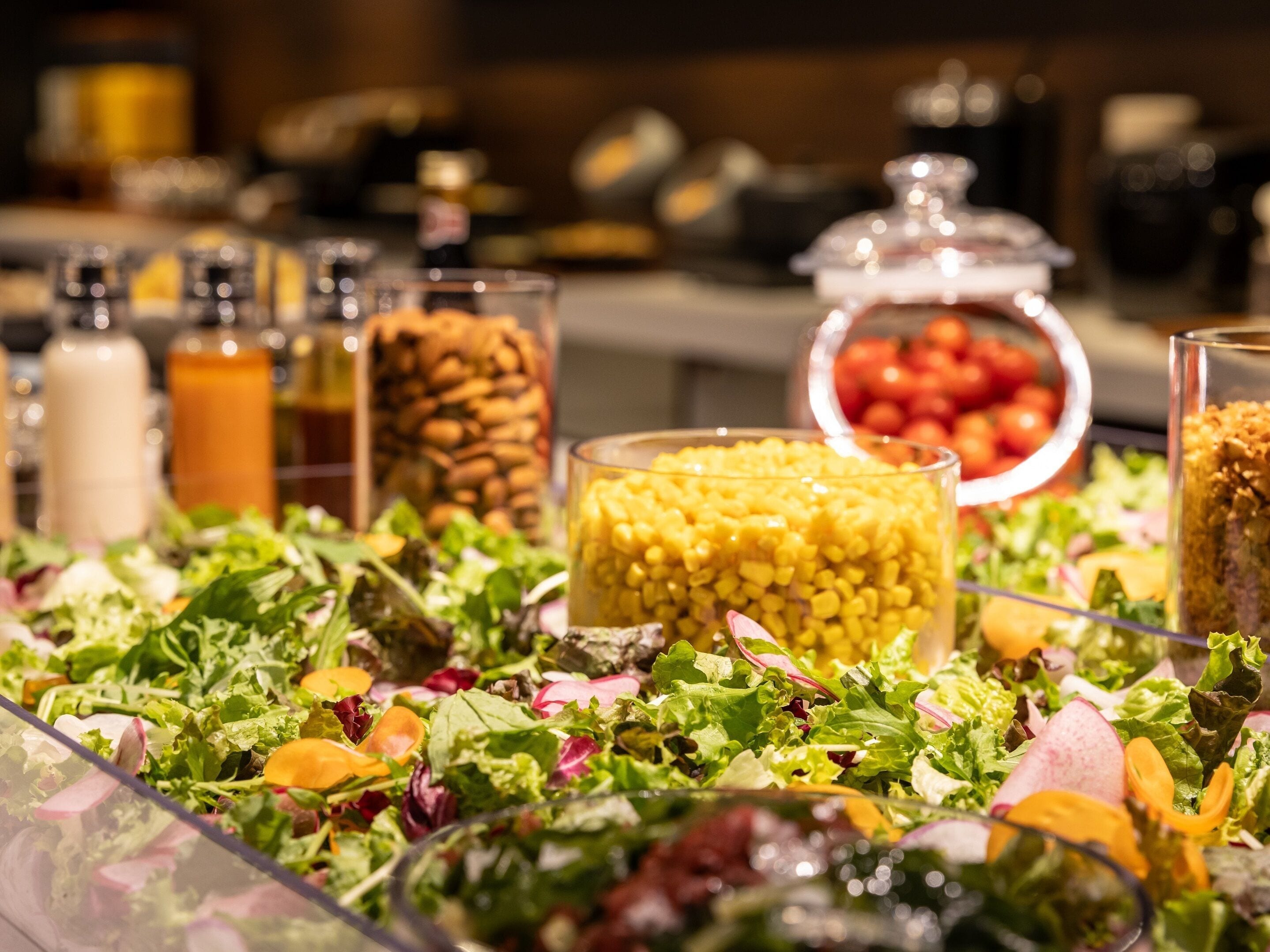 A buffet table with various food items including salads, fruits, and condiments.