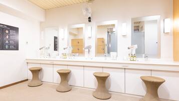 A modern bathroom with a large mirror, multiple sinks, and wicker stools.