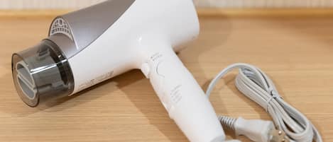 A Panasonic hair dryer with a cord and a power adapter on a wooden surface.