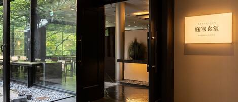 Un interior moderno con un vidrio que da a un área exterior, un letrero que indica un comedor jardín, y un diseño limpio y minimalista.