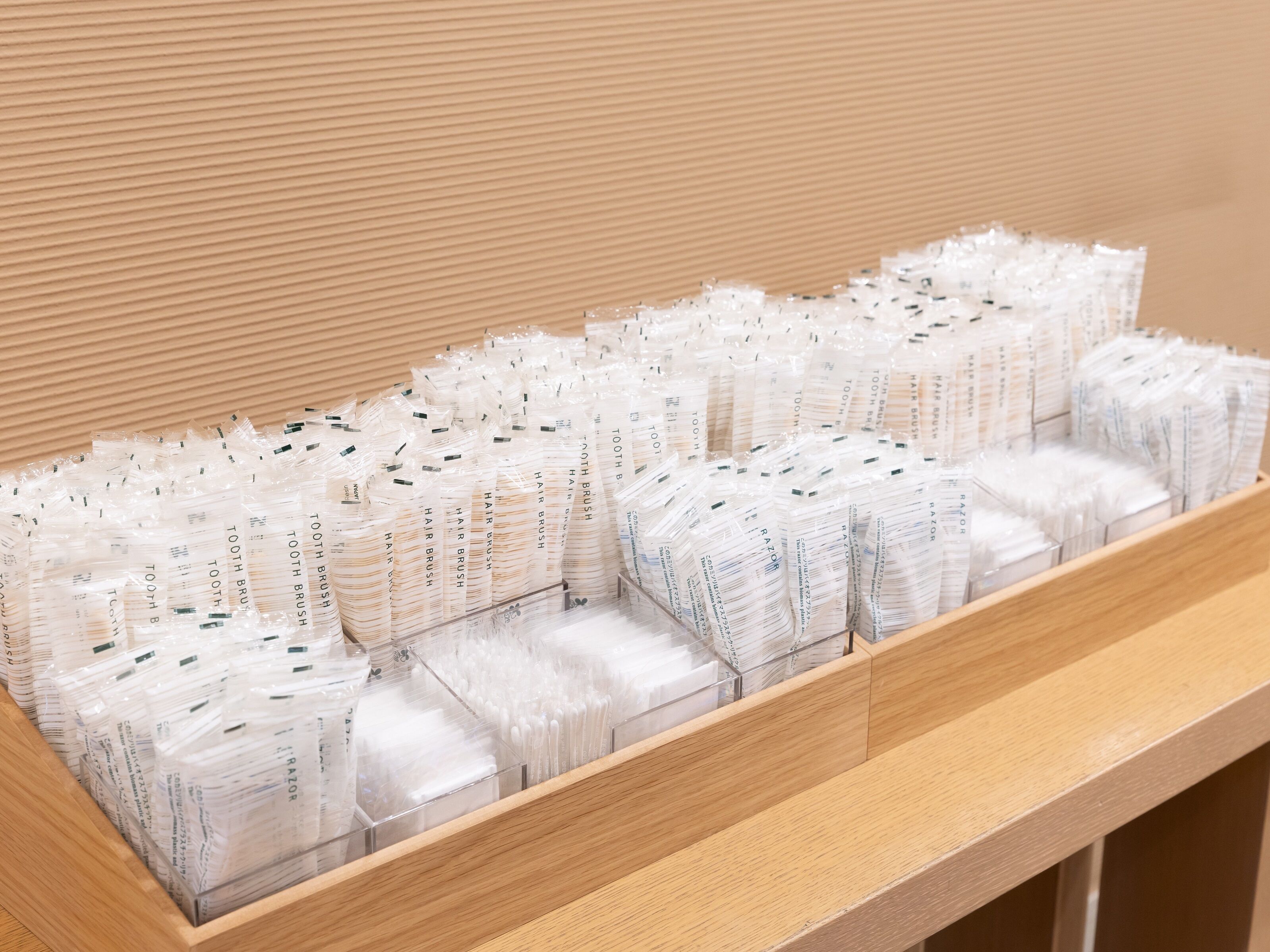 Una estantería de madera con paquetes ordenados de cepillos para el cabello y maquinillas de afeitar.
