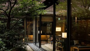 Een modern interieur met glazen wanden, een zithoek met kussens en een klein tuinpad.