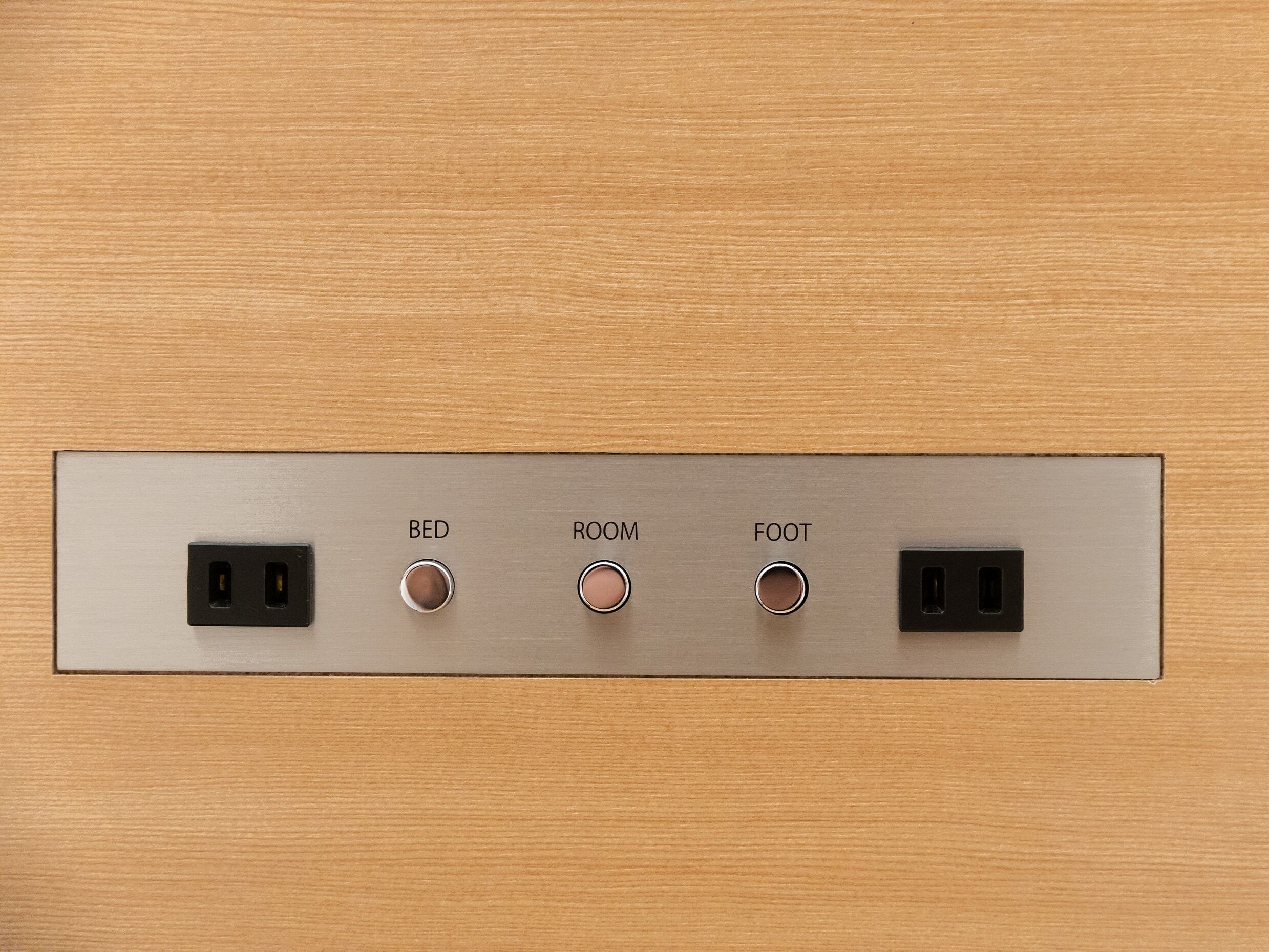 A wall-mounted electrical panel with labeled switches for BED, ROOM, and FOOT, and two USB ports.