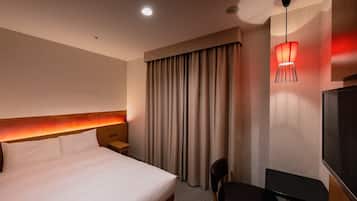 A hotel room with a large bed, a desk, a chair, a TV, and a red lamp.