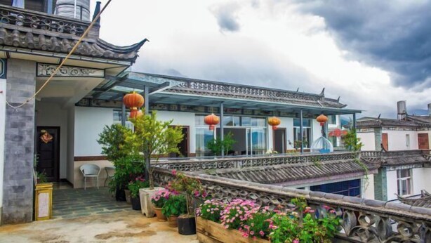 A traditional building with a tiled roof, a covered walkway, and potted plants. - Fushui Inn (Dali City)