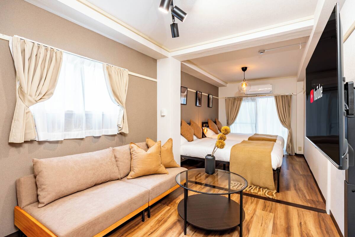 Une chambre d’hôtel moderne équipée d’un canapé, d’un lit, d’une télévision et d’une table basse en verre.