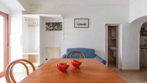 Un comedor con una mesa de madera, dos cuencos decorativos rojos, una silla azul y un cuadro en la pared.