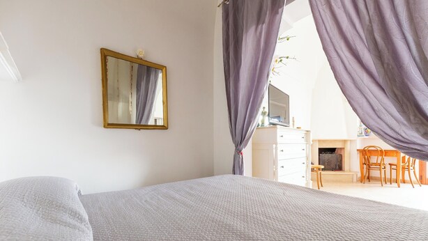Un dormitorio con cama, cómoda, espejo y vista a un comedor.