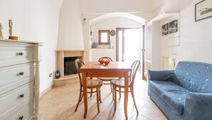 Un comedor con una mesa y sillas de madera, un sofá azul y una chimenea.