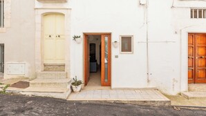 Un edificio blanco con una puerta amarilla, una puerta de madera y un ventanal pequeño.