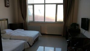 A hotel room with two beds, a TV, a radiator, and a window with curtains. - Zhenglan Qijiatai Business Hotel (Zhenglan Banner)