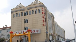 A multi-story building with a prominent entrance featuring a yellow archway with red lanterns. - Zhenglan Qijiatai Business Hotel (Zhenglan Banner)