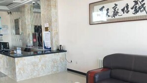 A reception area with a marble counter, a black leather sofa, and a framed calligraphy piece on the wall. - Zhenglan Qijiatai Business Hotel (Zhenglan Banner)