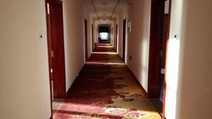 A long, narrow hotel corridor with a patterned carpet and wooden doors on either side. - Zhenglan Qijiatai Business Hotel (Zhenglan Banner)