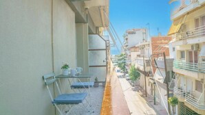 Una estrecha calle urbana flanqueada por edificios, una pequeña mesa con sillas y una planta en maceta.