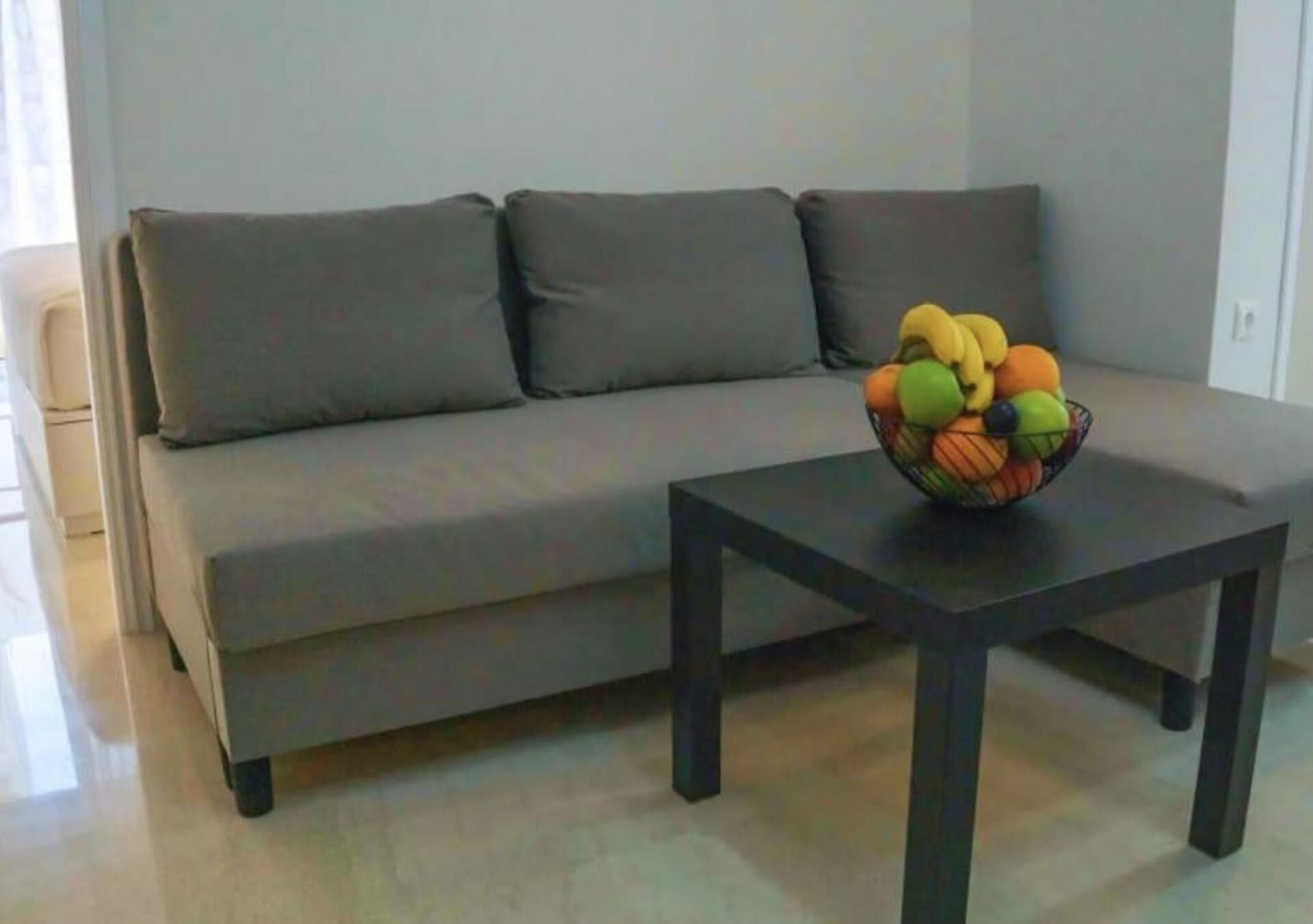 Een moderne woonkamer met een grijze bank en een zwarte salontafel.