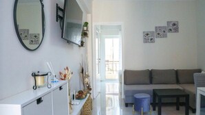 Una sala de estar moderna con un sofá, una mesa de centro, un televisor montado en la pared y una mesita auxiliar con adornos.