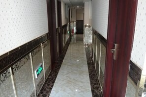 A marble hallway with a red door, white walls, and a patterned wall on the left. - Huizhou District South Gate Express Hotel (Huangshan City)