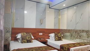 Una camera d'albergo con due letti, pareti in marmo, una testiera in legno e una tenda a motivi decorativi.