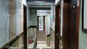 Un corridoio con pareti in marmo e ringhiera in vetro, che conduce a una scala e a un segnale di uscita.