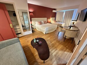 Habitación de hotel con una cama grande, un sofá pequeño, una mesa de centro redonda y un escritorio con una silla.