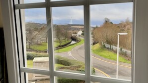 A view through a window of a road curving around a green area with a fence and a lamp post. - 17th Century Dovecot, 20 min to Edinburgh by train (Inverkeithing)