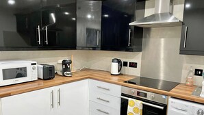 A modern kitchen with white cabinets, a Bosch microwave, a toaster, a coffee maker, an oven, and a washing machine. - 17th Century Dovecot, 20 min to Edinburgh by train (Inverkeithing)