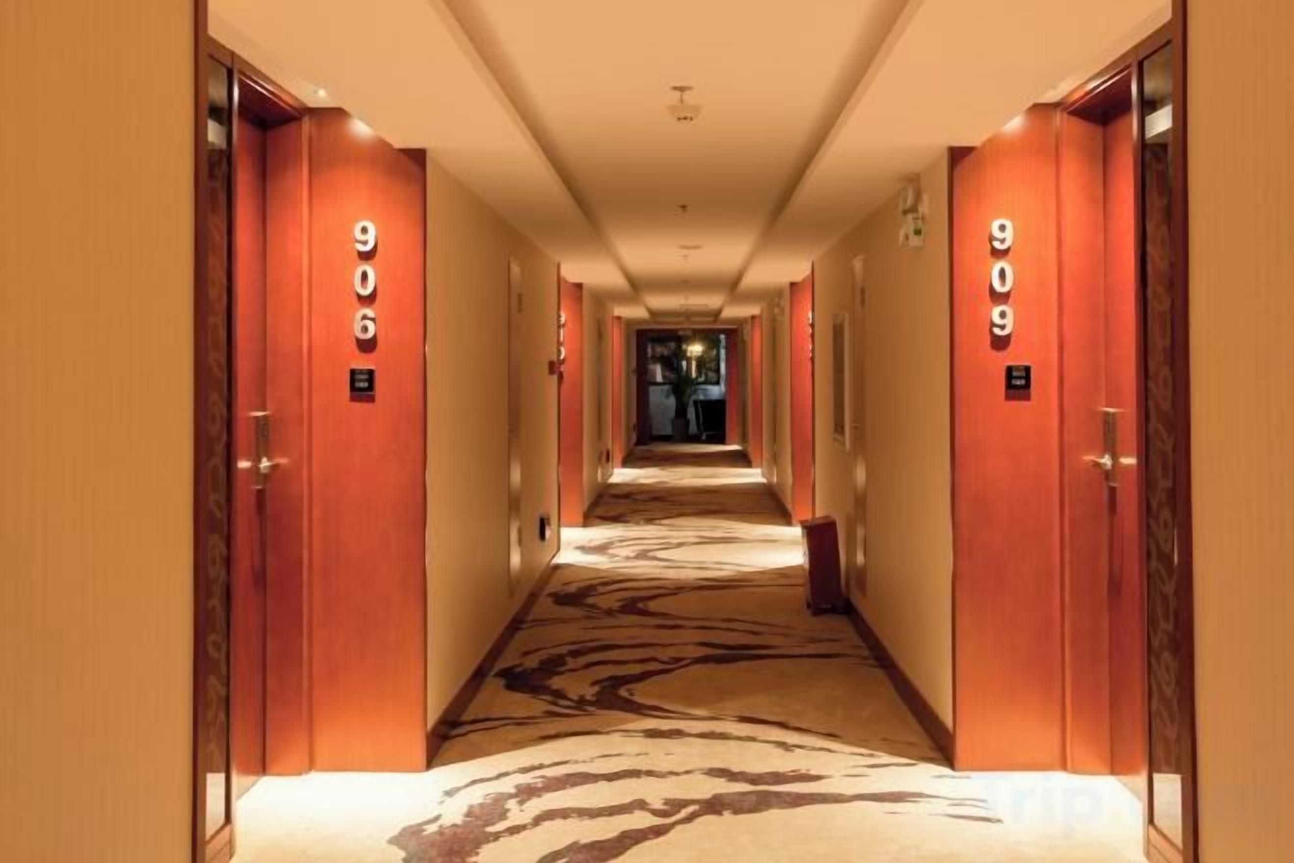 Un couloir d’hôtel avec des portes numérotées 906 et 909, un sol recouvert de moquette et un luminaire au plafond.