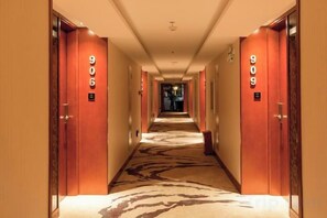 Ein Hotelgang mit Türen mit den Nummern 906 und 909, einem Teppichboden und einer Deckenleuchte.