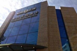 A modern hotel building with a prominent sign. - Chengjiang Manor Hotel (Chengjiang)