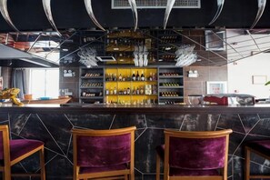 A bar area with a marble countertop, wooden chairs, and a variety of bottles on shelves. - Chengjiang Manor Hotel (Chengjiang)