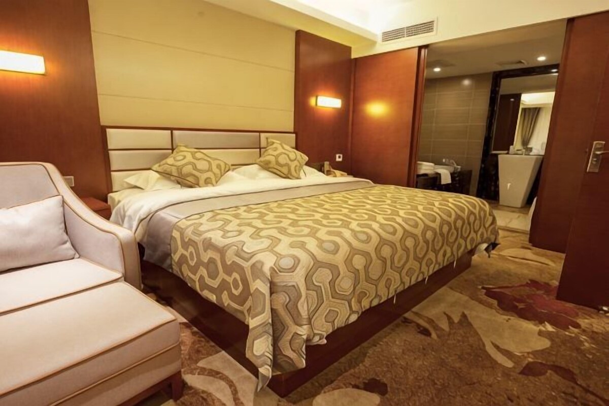 Une chambre d’hôtel avec un lit, une chaise, une salle de bain et un miroir.