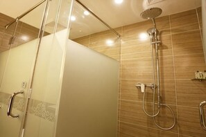 A shower with a glass door, a handheld showerhead, and a wall-mounted faucet. - Chengjiang Manor Hotel (Chengjiang)