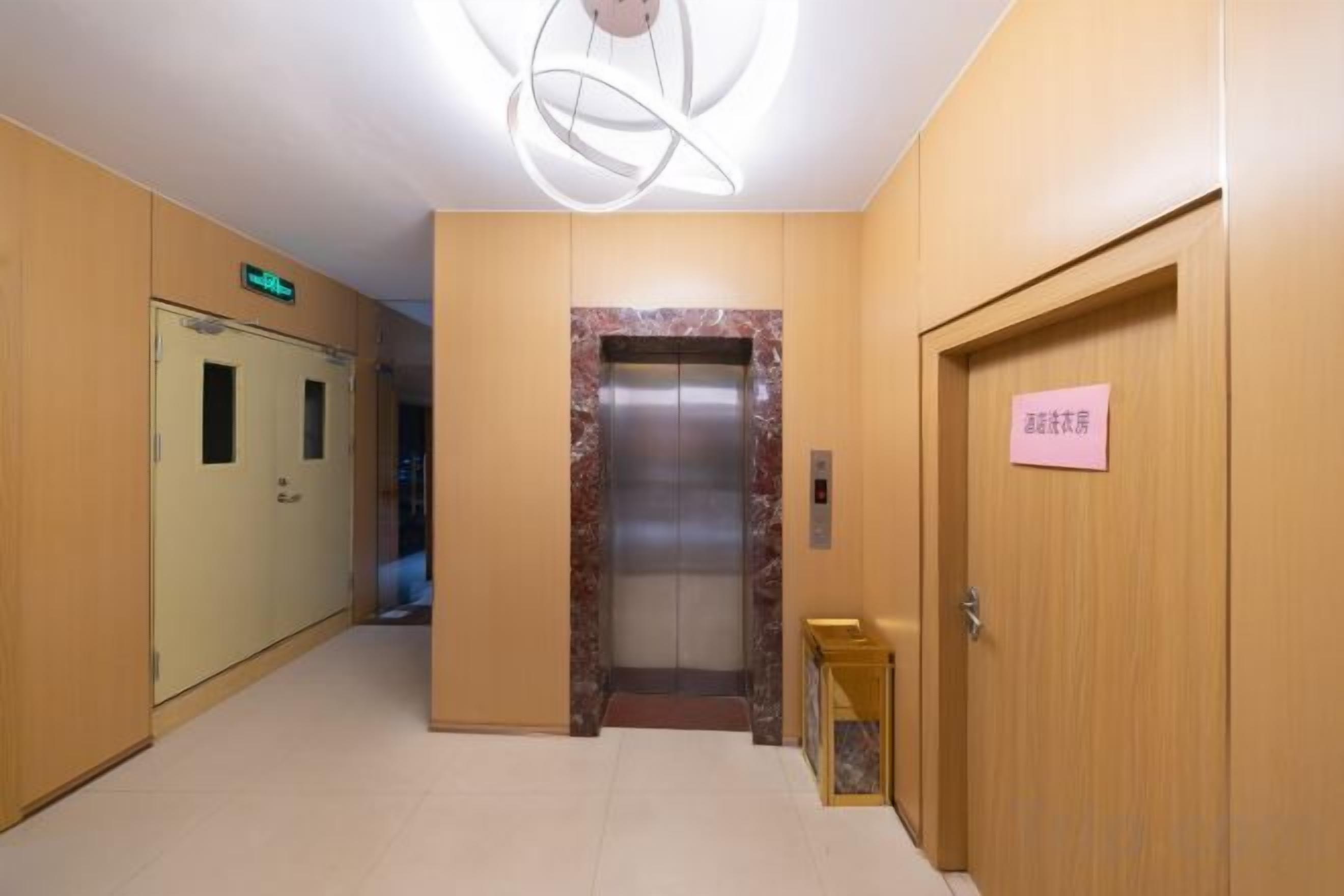 A hotel hallway with a reception desk, an elevator, and a door with a sign.