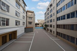 A multi-story residential building with a courtyard, balconies, and a clear sky.