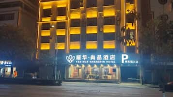 Un hotel con un letrero llamativo, un área de estacionamiento y una fachada bien iluminada.
