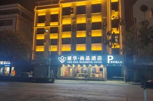 Un hotel con un letrero llamativo, un área de estacionamiento y una fachada bien iluminada.