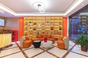 Un vestíbulo de hotel con una recepción, zona de estar y una pared con estanterías.