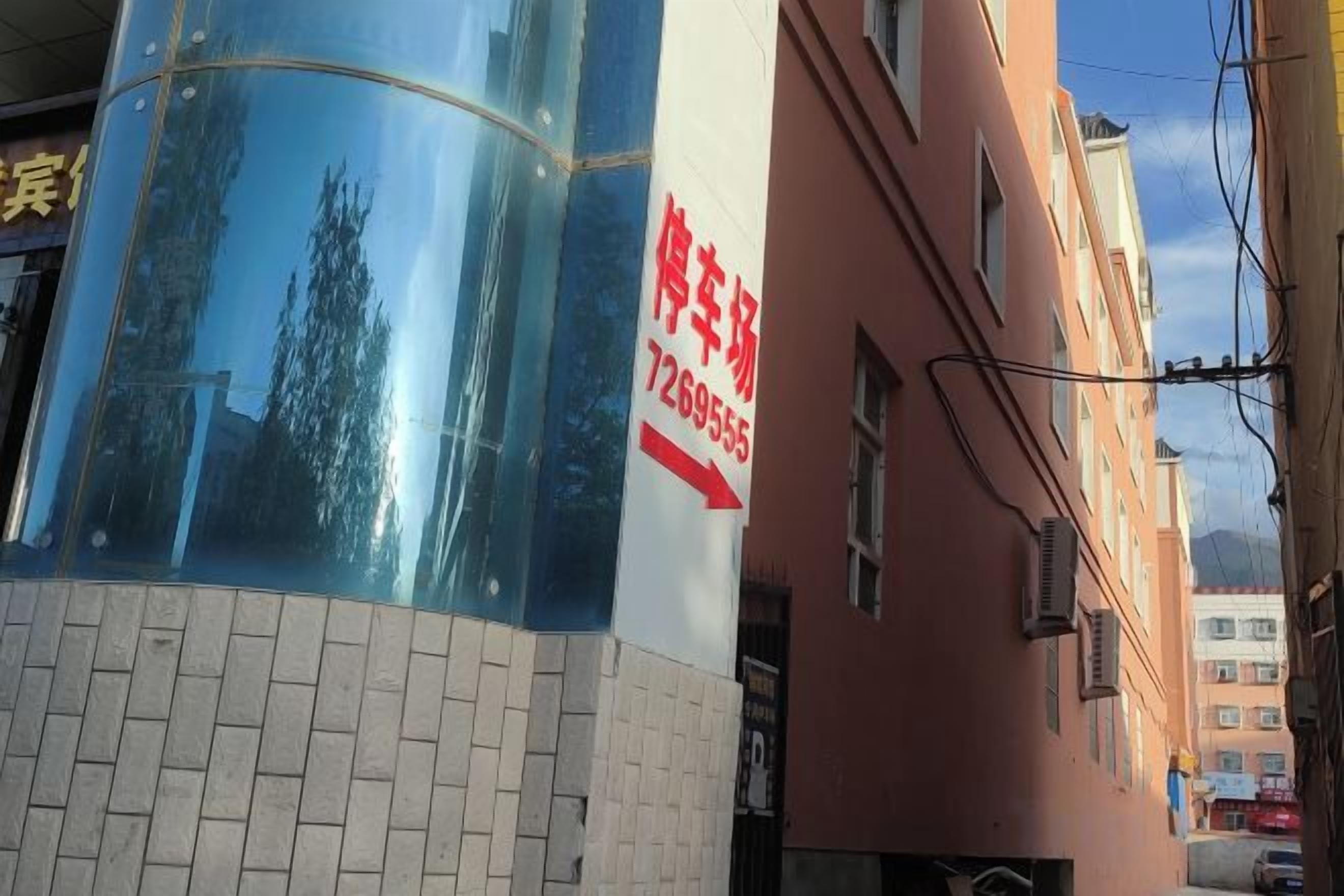 A building with a large glass window reflecting trees and a red sign with white text.
