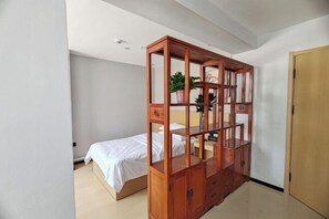 A bedroom with a wooden canopy bed, a bedside table, a wardrobe, and a potted plant. - Balikun Hancheng Hotel (Barkol)