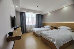 A hotel room with two beds, a TV mounted on the wall, a small table with a plant, and a window with curtains. - Balikun Hancheng Hotel (Barkol)